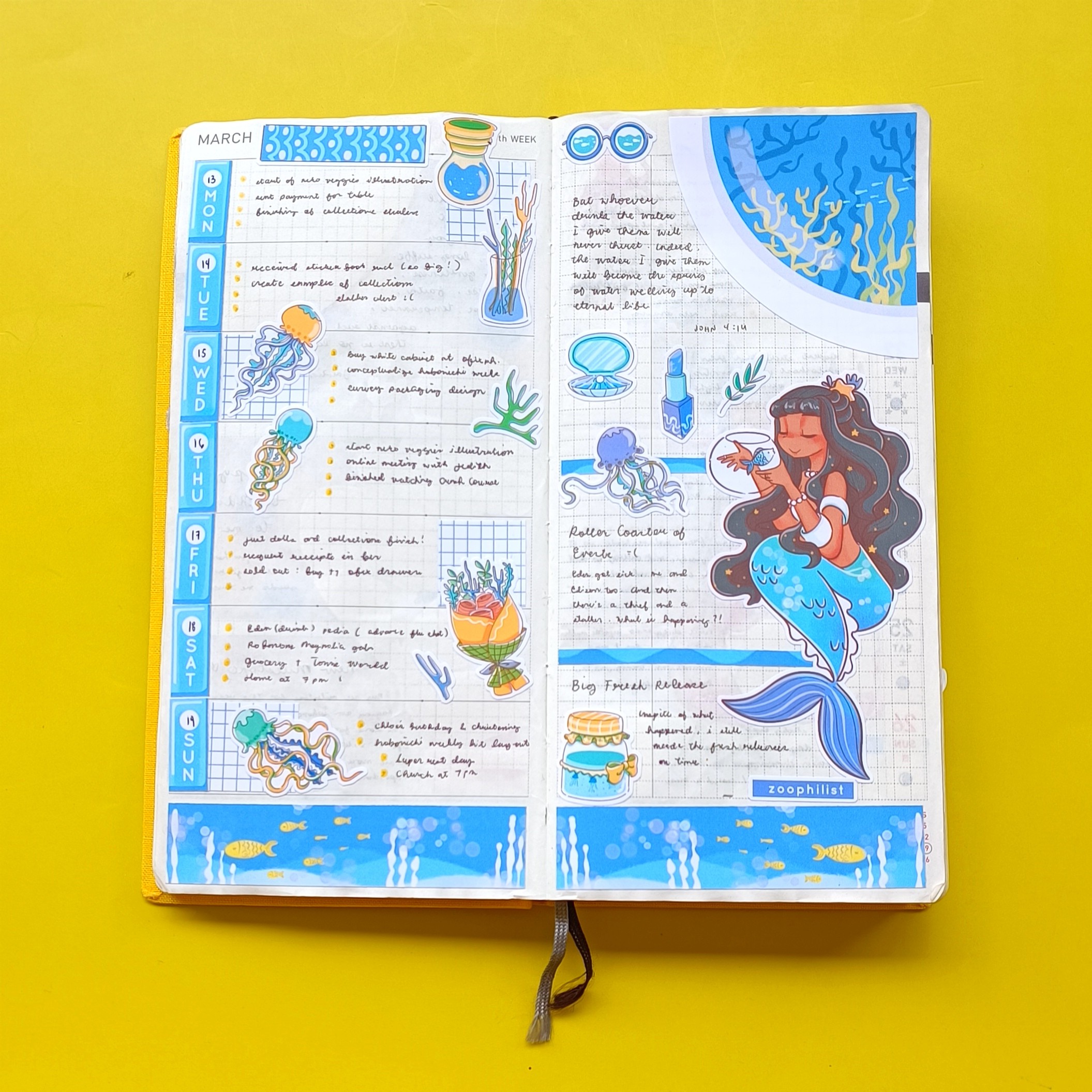 Open journal with blue and yellow decorations, handwritten notes, and illustrations of underwater scenes and a mermaid, on a yellow background.