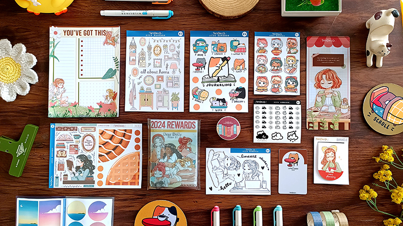 Flat lay of colorful stationery, notebooks, stickers, and decorative items on a wooden surface.